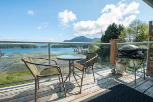 a grill and chairs on a deck with a view of a river at Waterfront Condo by OnlyBC 202 in Tofino