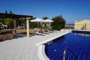 a swimming pool with chairs and umbrellas on a patio at Rhodes Demetrius Luxury Private Villa in Kalathos