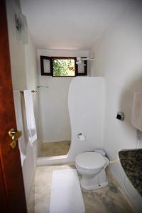 a small bathroom with a toilet and a window at Canto do Sabiá Caraíva in Caraíva