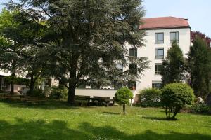 ein Gebäude mit einem Baum und Bänken auf einem Feld in der Unterkunft Christkönigshaus in Stuttgart
