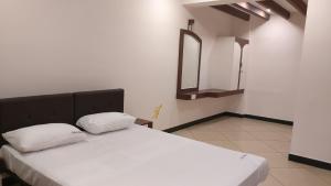a bedroom with a bed with two pillows and a mirror at Ashok Bhavan in Madurai