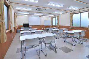 ein Klassenzimmer mit Tischen und Stühlen in einem Klassenzimmer in der Unterkunft Yawatajuku Dai-ichi Hotel in Ichihara