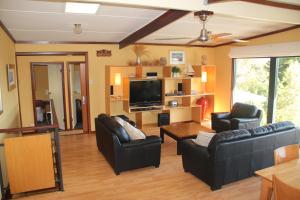 a living room with black leather furniture and a flat screen tv at Gabbadah Beach House in Guilderton