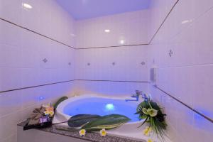 ein weißes Bad mit einer Badewanne mit Blumen in der Unterkunft Hotel Sulata Ashikaga (Adult Only) in Ashikaga
