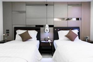 Duas camas num quarto com lençóis brancos e almofadas castanhas em The Connex Asoke em Bangkok