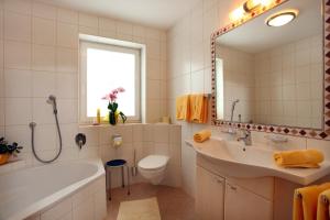 a bathroom with a tub and a sink and a toilet at Appartements Oberhauser in Westendorf