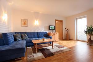 a living room with a blue couch and a table at Appartements Oberhauser in Westendorf