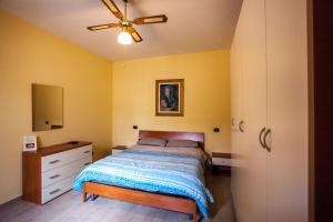 Schlafzimmer mit einem Bett, einer Kommode und einem Deckenventilator in der Unterkunft Erasippe Residence in Locri