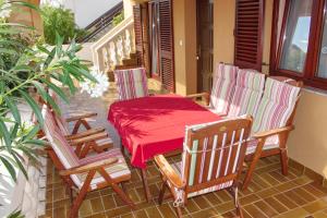 une terrasse couverte avec 2 chaises et une table avec un tissu de table rouge dans l'établissement Apartments Juracak, à Nin