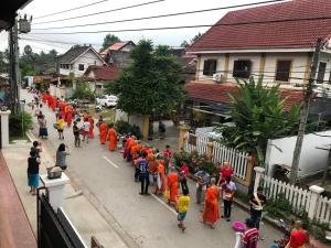 un grupo de personas con batas naranjas caminando por una calle en Jasmine Luangprabang Hotel en Luang Prabang