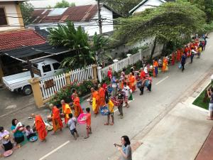 um grupo de pessoas em vestes laranja andando por uma rua em Jasmine Luangprabang Hotel em Luang Prabang