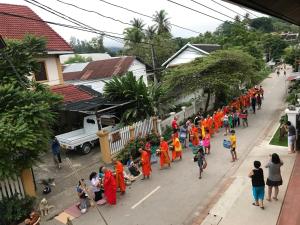 un grupo de personas con batas naranjas caminando por una calle en Jasmine Luangprabang Hotel en Luang Prabang