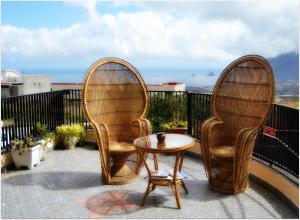 Duas cadeiras de vime e uma mesa na varanda em Apartamentos Jucar em Frontera