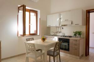 Stella CilentoにあるAppartamenti Droroのキッチン(白いテーブル、椅子、テーブル、コンロ付)