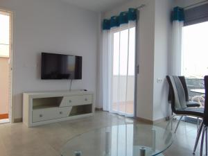 a living room with a tv and a glass table at Villa Vistamar in Puerto de Mazarrón