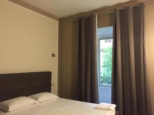 Schlafzimmer mit einem Bett und einem Fenster mit Vorhängen in der Unterkunft Candia Rooms in Rom