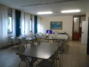 a dining room with tables and chairs and windows at Ostello Angolo Verde in Angolo Terme