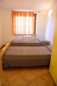 two beds in a room with a window at Nuova Valmar Villa Condominio Rei Sole in Costa Rei