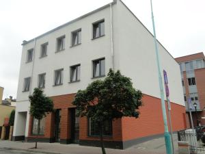 a white building with a tree in front of it at Apartamenty Brzezinski in Września