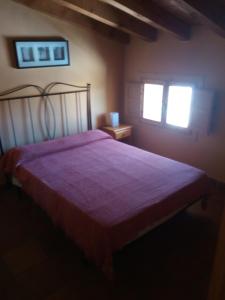 a bedroom with a bed with a red bedspread and two windows at El Egio in Cervera de Buitrago