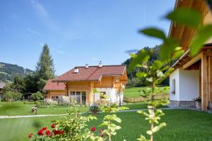 a wooden house with a green yard with flowers at Lehenriedl Chalet in Wagrain