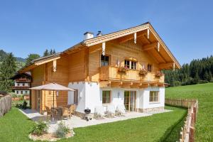 a wooden house with a balcony and a table and chairs at Lehenriedl Chalet in Wagrain