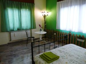 a bedroom with green walls and a bed and a table at In Giardino B&B in Cassina deʼ Pecchi