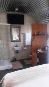 a bathroom with a tub and a sink and a bed at Conductor's Inn in Tsumeb