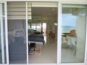 a bedroom with a bed and a glass door at Sunshine Beach Condotel by Lux in Na Jomtien