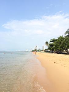 a beach with people walking in the water at Sunshine Beach Condotel by Lux in Na Jomtien