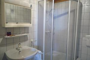 a white bathroom with a shower and a sink at Alkira in Sankt Anton am Arlberg