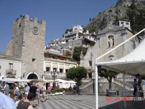 a large building with a clock tower and a mountain at Taormina castle and sea view in Taormina