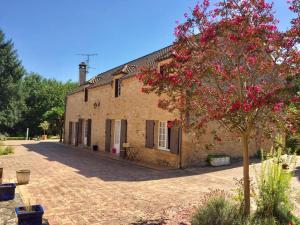 La Chapelle-AubareilにあるGite le domaine Aubazenの赤い花の木が目の前にある建物