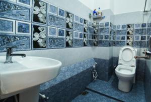 La salle de bains est pourvue d'un lavabo et de toilettes avec du carrelage bleu. dans l'établissement Thoms Beach Homestay, à Alappuzha