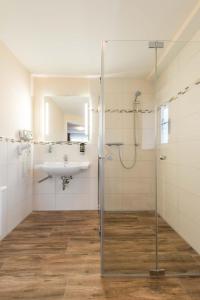 a bathroom with a glass shower and a sink at Abasto Hotel & Spa Maisach in Maisach