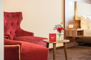 ein Zimmer mit einem Stuhl und einer Vase aus Blumen auf einem Tisch in der Unterkunft Abasto Hotel & Spa Maisach in Maisach