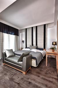 Olympus Thea Boutique Hotel في بلاتامون: غرفة نوم بسرير واريكة جلدية