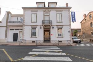 a white building on the corner of a street at Hôtel Mets et Plaisirs in Mazamet