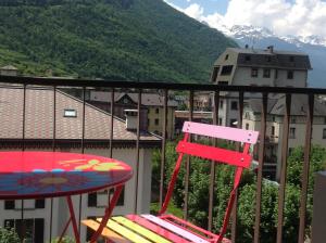 a chair and a table on a balcony with mountains at Appartamento Elisa 50m Trenino Rosso in Tirano