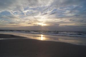 una puesta de sol en una playa con el océano y las nubes en l'Hippodrome, en Bredene
