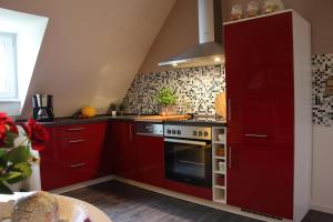 eine Küche mit roten Schränken und einem Herd in der Unterkunft Haus Kolmesfeld in Sensweiler