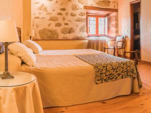 um quarto com uma cama e uma mesa com um candeeiro em Posada Real La Casa de Arriba em Navarredonda de Gredos