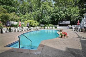 a swimming pool with tables and chairs and flowers at Auberge Lakeview Inn in Lac-Brome