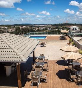 a patio with tables and chairs and a pool at Mirante Flat in Ouro Branco