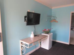 um quarto com uma televisão numa parede azul em Starlight Inn Van Nuys em Van Nuys