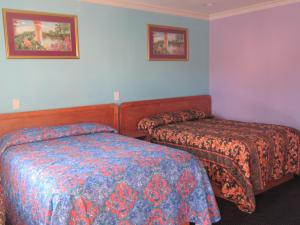 a hotel room with two beds and paintings on the wall at Starlight Inn Van Nuys in Van Nuys