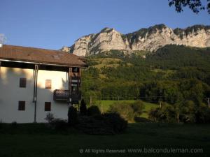 a white house with a mountain in the background at Between lake en ski resort in Thollon