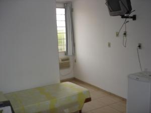 Habitación con TV, mesa y ventana. en Delmus Hotel, en Conselheiro Pena