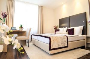 バーデン・バーデンにあるホテル メルクール - スーペリアのベッドとデスクが備わるホテルルームと