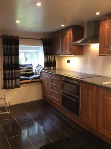 uma cozinha com armários de madeira, uma janela e um fogão em White Cottage Askham em Askham